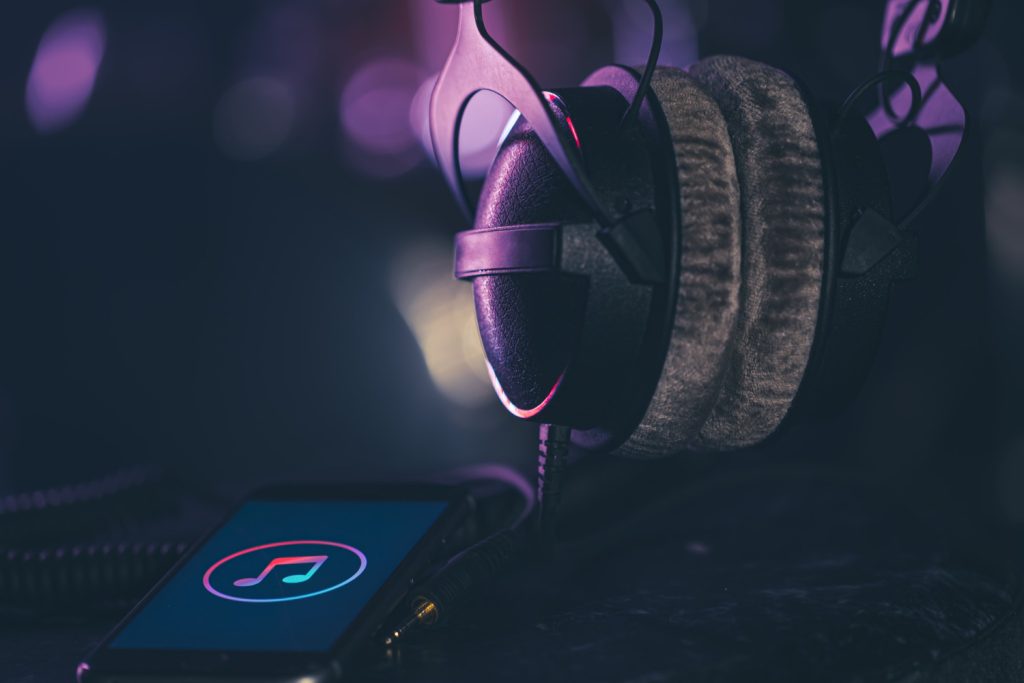 Auriculares y smartphone con icono de música, representando la experiencia musical de Kovak Collective